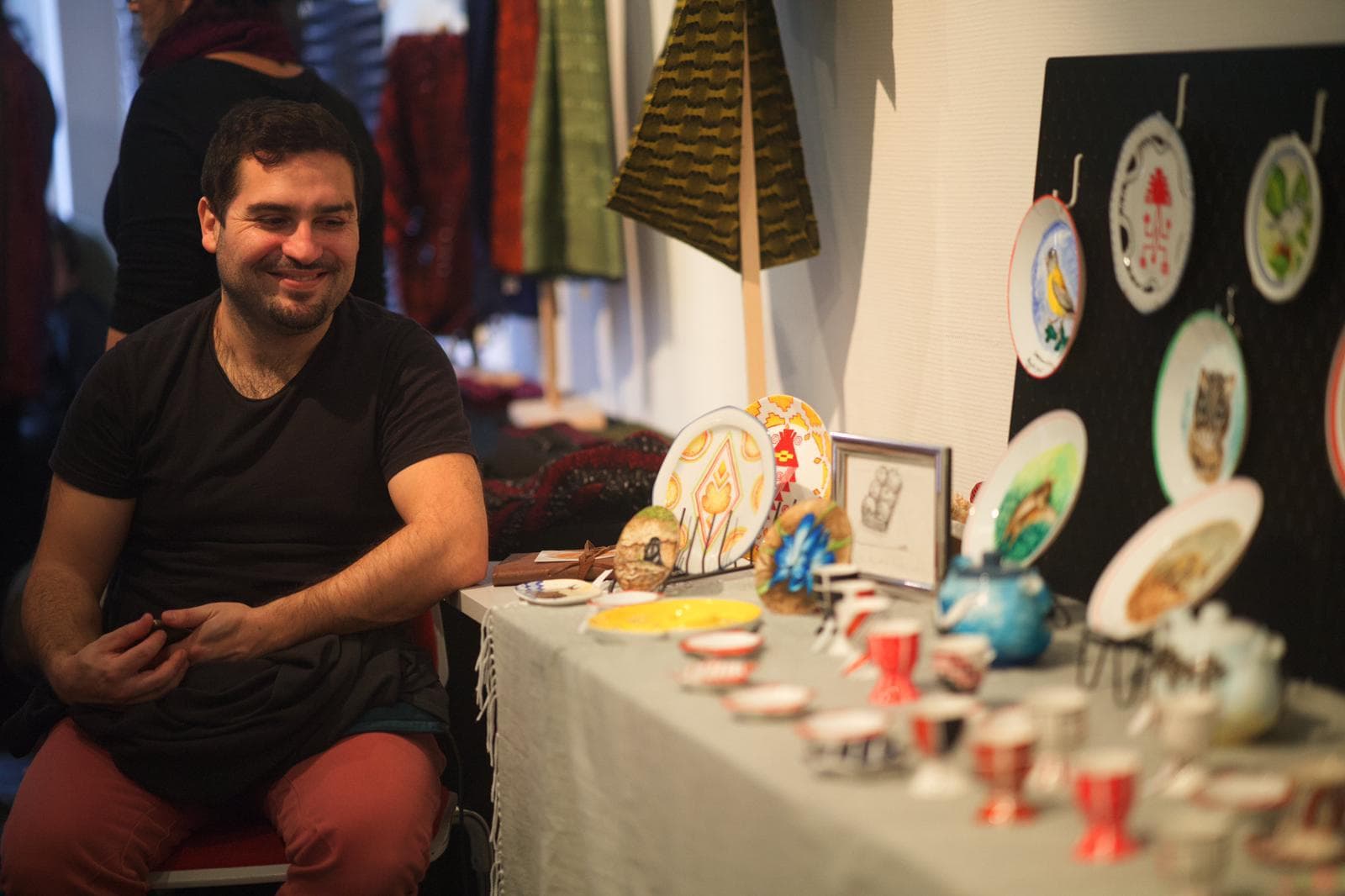 Ein Künstler an seinem Stand mit handbemaltem Geschirr auf dem Markt 2022