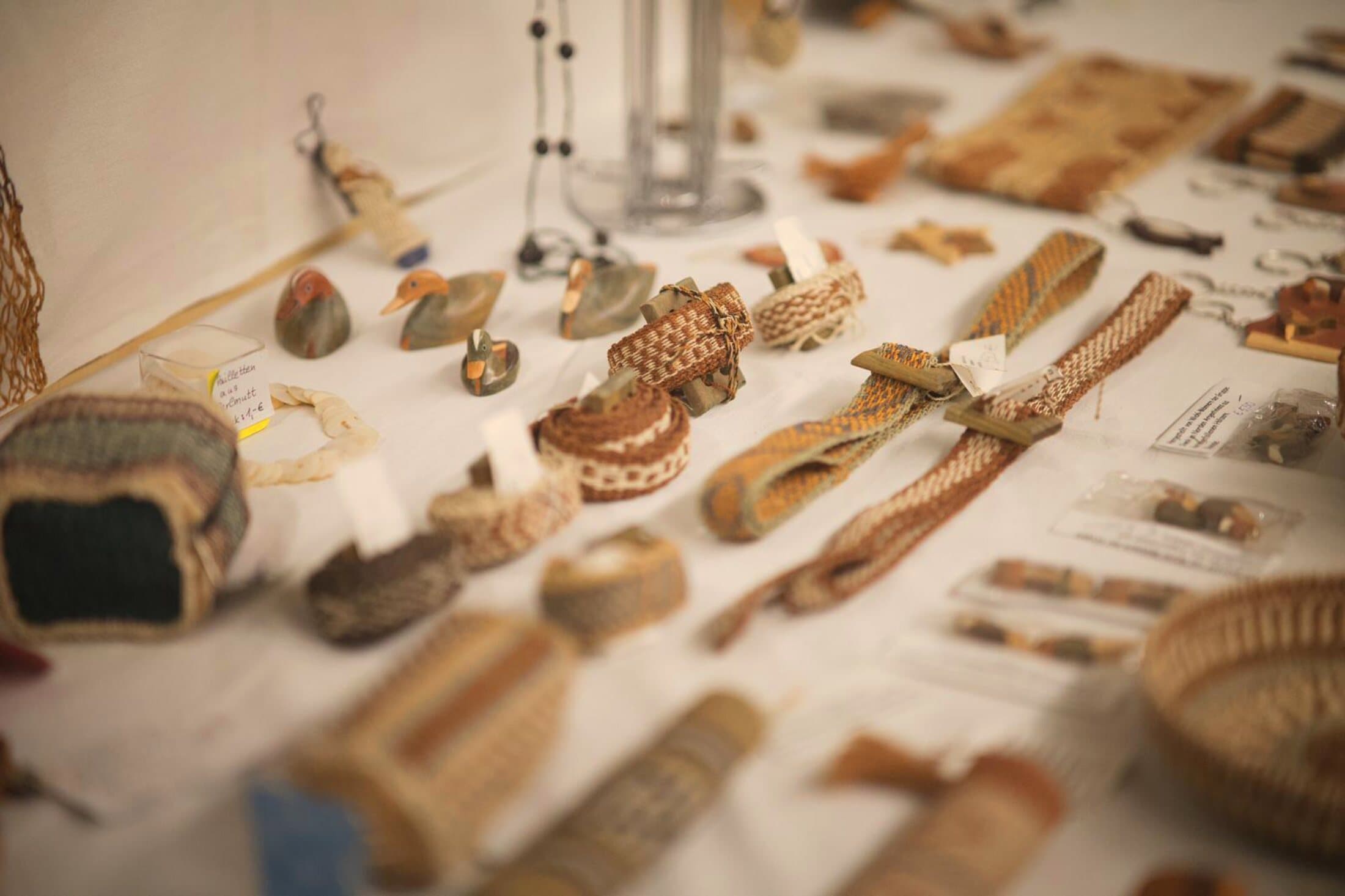 Lateinamerikanisches Kunsthandwerk – gewebte Armbänder, Körbe, Schmuck und geschnitzte Holzfiguren – auf dem Tisch eines Marktstands